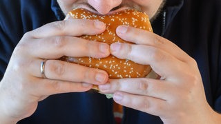 Nahaufnahme: Ein Mann beißt in einen Hamburger