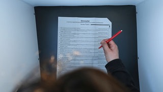 Eine Frau gibt in einer Wahlkabine ihre stimme zur Europawahl 2024 ab. 