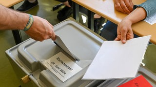 Ein Mann wirft seine Stimme während der Europawahl in eine Wahlbox.