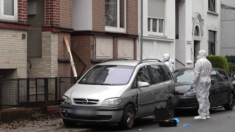 Zwei Spurensucher der Polizei stehen vor einem Hauseingang.