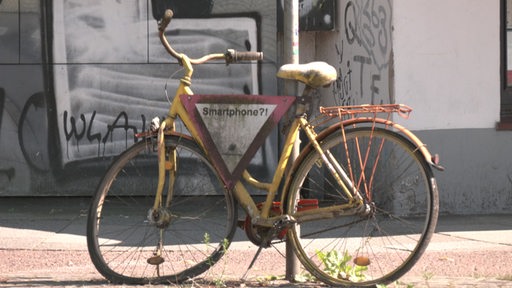 Ein schrottes Fahrrad angeschlossen an einer Laterne.