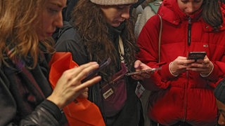 Eine Gruppe von jungen Frauen schaut auf ihre Smartphones