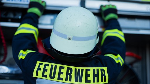 Ein Feuerwehrmann holt Equipment aus einem Einsatzfahrzeug.