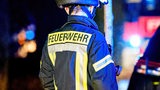 Der Schriftzug "Feuerwehr" steht auf der Jacke eines Feuerwehrmanns.