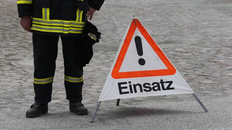 Ein Mensch in Feuerwehruniform steht neben einem Warnschild.