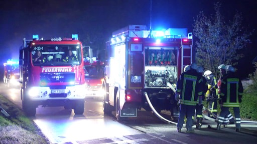 Mehrere Feuerwehrautos mit Blaulicht während eines Einsatzes bei Nacht