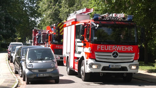 Drei große Einsatzwagen der Feuerwehr stehen hintereinander auf einer Straße.
