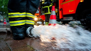 Wasser läuft aus dem Schlauch an einer Feuerwehrpumpe.