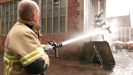 Ein Feuerwehrmann spritz die Stadtmusikanten sauber.