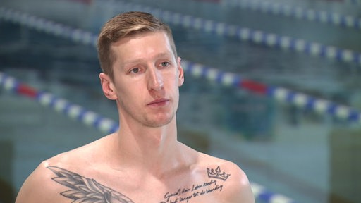 Eine Portraitaufnahme von Florian Wellbrock vor einem Schwimmbecken