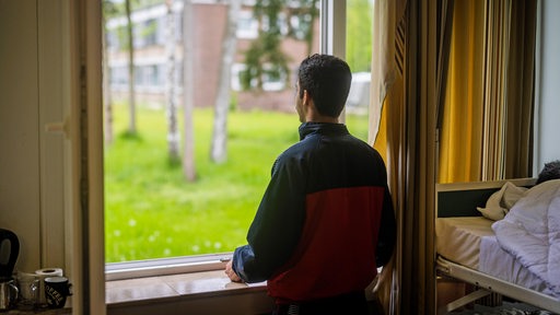 Ein junger syrischer Flüchtling blickt aus dem Fenster seiner Unterkunft.