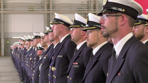 Viele Marineflieger-Piloten stehen in ihren Uniformen nebeneinander aufgereiht.
