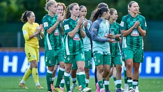 Die Bundesliga-Fußballerinnen von Werder Bremen schlendern applaudierend über den Platz.