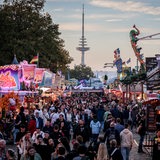 Besucher gehen zwischen Ständen und Fahrgeschäften auf dem 989. Freimarkt. 