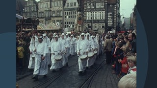 Die Archivaufnahme einer Gruppe weiß bekleideter Menschen mit Trommeln auf dem Bremer Freimarktsumzug