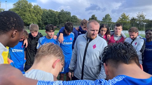 Trainer Denis Spitzer vom Blumenthaler SV umringt von seinen U17-Fußballern bei einer Ansprache.