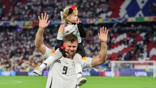 Der deutsche Nationalspieler Niclas Füllkrug trägt jubelnd nach dem Auftaktsieg gegen Schottland seine kleine Tochter auf den Schultern durchs Stadion.