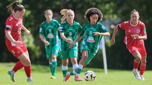 Amira Arfaoui von Werder Bremen führt den Ball eng am Fuß. Die Kölner Gegenspielerinnen nähern sich ihr.