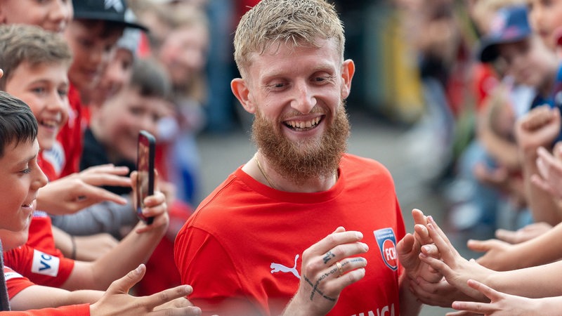 Heidenheim-Spieler Jan-Niklas Beste genießt das Bad in der Menge der Fans am Trainingsrand.