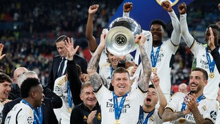 Toni Kroos hebt den Champions-League-Pokal mit beiden Armen hoch. 