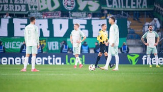 Werders Fußball-Profis stehen nach dem Pokal-Aus gegen Bielefeld frustriert und ratlos auf dem Rasen herum.