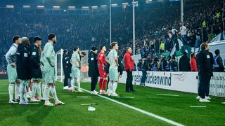 Werder-Spieler stehen nach dem Pokal-Aus in Bielefeld vor dem Bremer Gästeblock und lassen sich von ihren Fans anzählen und beschimpfen.