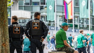 Polizisten stehen vor dem Weser-Stadion. Im Hintergrund sind Fans unterwegs.