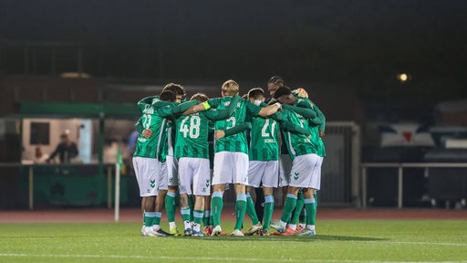 Werders U23 Fußballer stehen vor dem Anpfiff im Kreis zusammen, um sich einzuschwören.