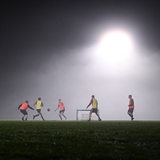 Mehrere Fußballer trainieren im Flutlicht.