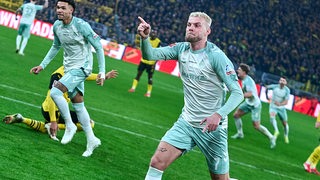 Werder-Stürmer Marvin Ducksch rennt jubelnd nach seinem Tor gegen Dortmund über das Spielfeld und deutet mit seinem Zeigefinger nach vorne.