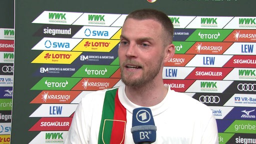 Werder-Stürmer Marvin Ducksch lächelt beim Interview nach dem Spiel vor einer Werbewand.
