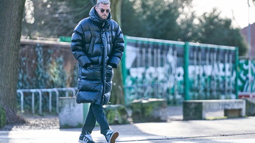 Werder-Stürmer Marvin Ducksch auf dem Weg zum Weser-Stadion in einem dunklen Daunenmantel und mit Sonnenbrille.