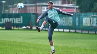 Werder-Stürmer Marvin Ducksch reckt im Training das Bein weit hoch, um einen heranfliegenden Ball zu treffen.