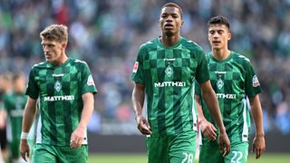 Die Werder-Profis Jens Stage, Skelly Alvero und Julian Malatini gehen mit angespannten Mienen zur Halbzeitpause in die Kabine.