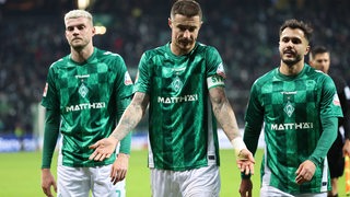 Werder-Kapitän Marco Friedl verlässt unzufrieden gestikulierend nach dem Remis gegen Stuttgart das Spielfeld, neben ihm Marvin Ducksch und Leonardo Bittencourt.