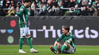 Die Werder-Fußballprofis Leonardo Bittencourt und Niklas Stark stehen und sitzen frustriert auf dem Rasen nach der Niederlage gegen Hoffenheim.