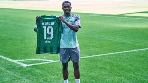 Werder-Neuzugang Derrick Köhn hält bei seiner Vorstellung im Weser-Stadion sein Trikot mit der Rückennummer 19 hoch.