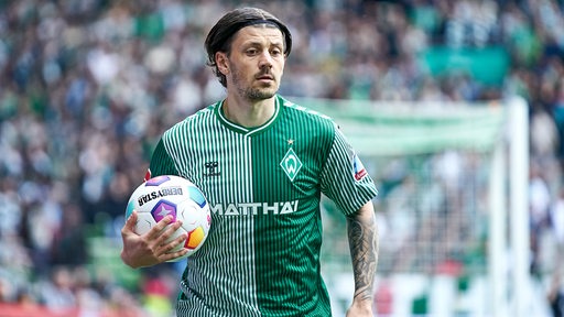 Werder-Spieler Dawid Kownacki hält einen Fußball in der Hand.