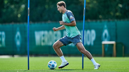 Werder-Spieler Stark dribbelt im Training mit dem Ball um zwei Stangen herum.