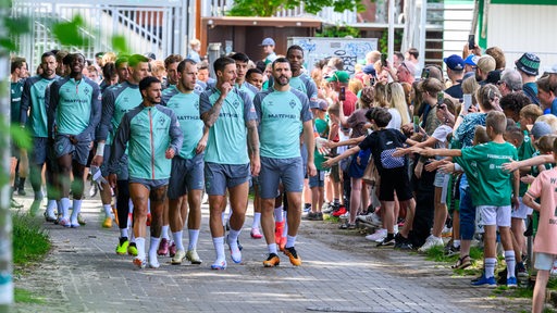 Viele Fans säumen den Weg, als die Werder-Profis zum Trainingsauftakt der neuen Saison zum Platz gehen.