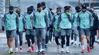 Die Werder-Spieler geht in leichten Schnellfall gemeinsam den Weg hinunter zum Trainingsplatz.