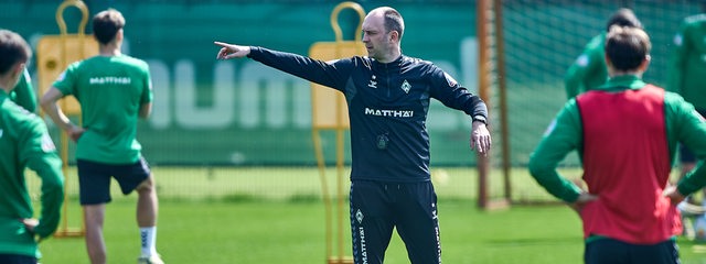 Werder-Trainer Ole Werner gibt seinen Spielern auf dem Trainingsplatz mit dem ausgestreckten rechten Arm die Richtung vor.