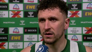 Werder-Profi Milos Veljkovic steht nach einem Spiel vor einer Werbewand beim Interview.