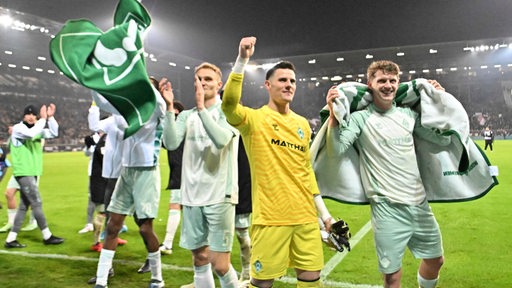 Werder-Spieler um Torwart Michael Zetterer stehen im Hamburger Millerntor vor dem Fanblock und feiern ausgelassen ihren Sieg.