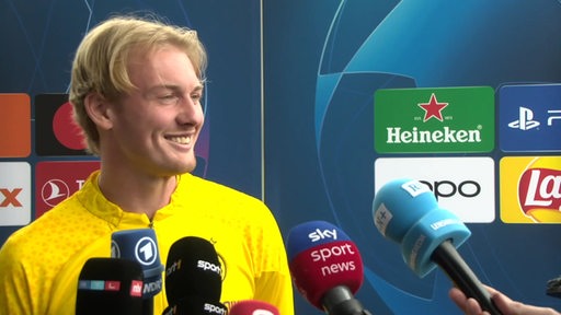 Der Borussia Dortmund Fußballspieler Julian Brandt lächelt beim Interview.