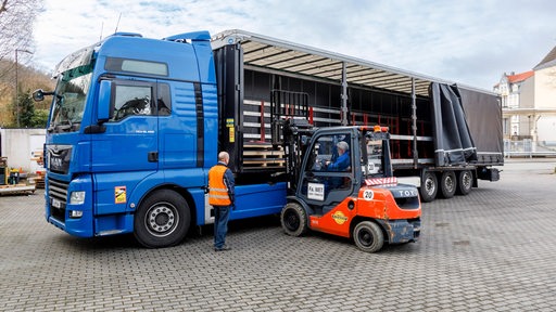 Ein Gabelstaplerfahrer belädt einen Lastwagen.