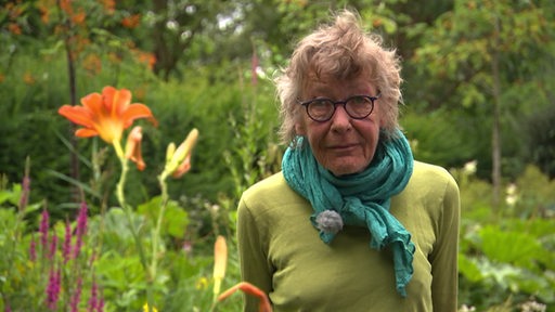 Die Gartenexpertin Cordula Hamann in einem blühenden Garten.