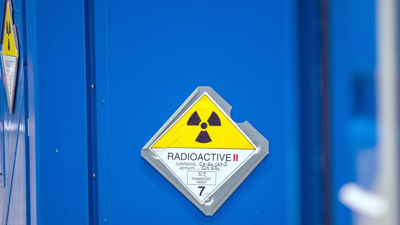 Ein Gelbes Warnschild auf einem blauen Container, auf dem "Radioaktiv" steht