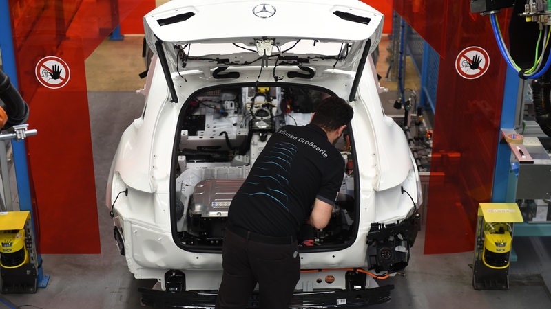 Ein Mitarbeiter von Mercedes-Benz in Bremen arbeitet an einem C-Klasse Hybrid Modell und bereitet den Einbau der Batterie vor.