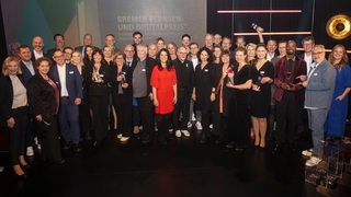 Gruppenfoto der Gewinner und Gewinnerinnen des Bremer Fernseh- und Digitalpreises 2024 auf der Bühne